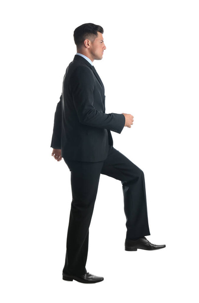 Businessman imitating stepping up on stairs against white background. Career ladder concept - Foto, immagini