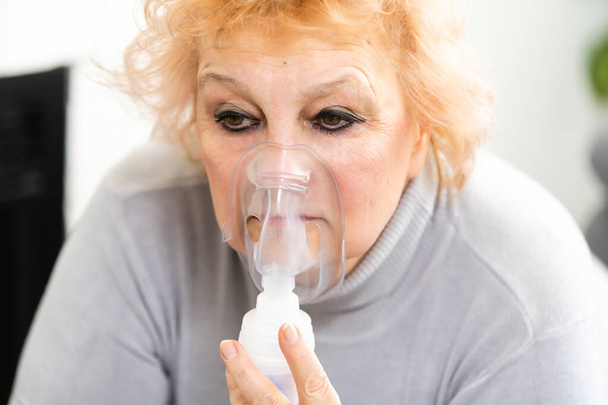 Oudere vrouw die inhalatie maakt, oudere vrouw en vernevelaar - Foto, afbeelding
