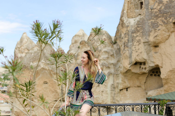 Kavkazská dívka stojící se starobylým jeskynním městem na pozadí v Kappadokii, Turecko. - Fotografie, Obrázek
