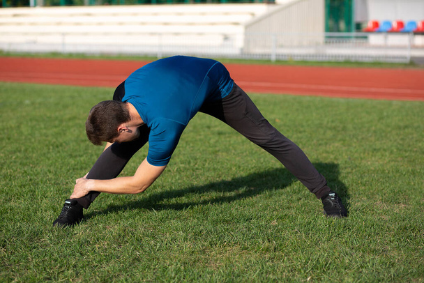 Sportos férfi nyújtózkodik edzés után a stadionban. A szöveg helye - Fotó, kép