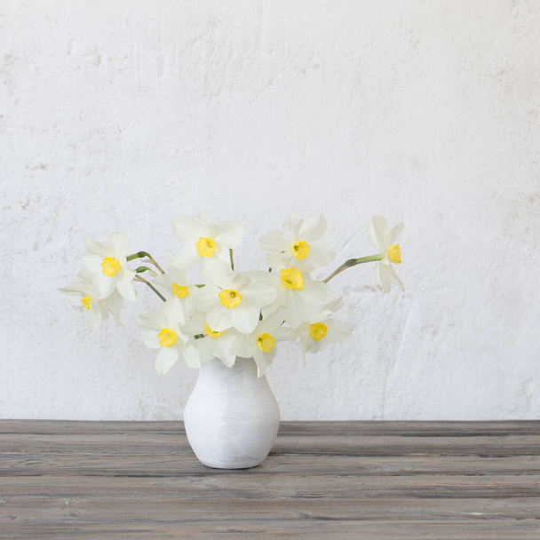 narcissus in vase on wooden table - Foto, afbeelding