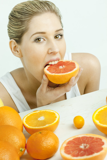 Portrait of young woman eating grapefruit - Foto, Bild