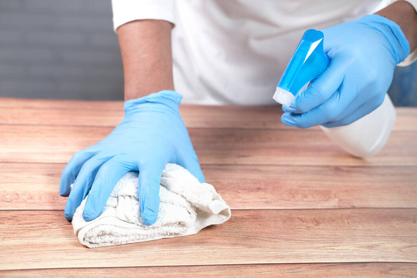 mão em luvas descartáveis usando spray desinfetante para limpar a superfície da mesa - Foto, Imagem