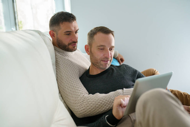coppia gay consultando i loro piani di viaggio insieme con un tablet digitale. - Foto, immagini