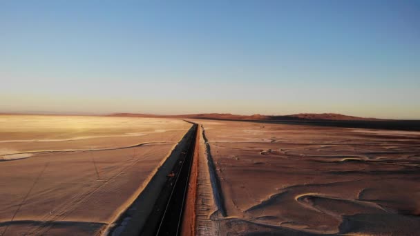Drone flight following black asphalt road across orange and brown empty desert - Materiaali, video
