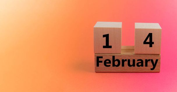 Gradient light orange pink background with wooden block calendar with date February 14 with copy space and space for your text - Фото, изображение