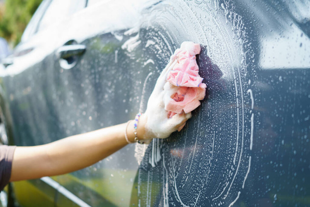 女性の手は車を洗うためのマイクロファイバー布を保持します。概念消毒と車両の消毒洗浄 - 写真・画像