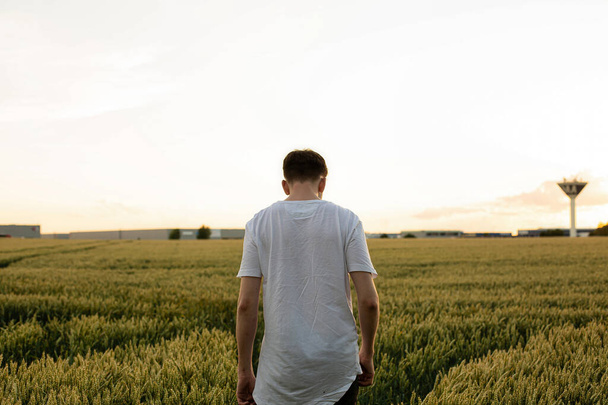Giovane ragazzo europeo bianco con i capelli biondi con campo dietro dalla schiena - Foto, immagini