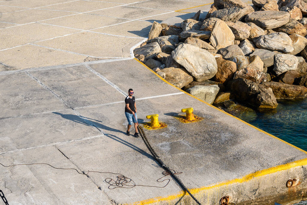 Sikinos, Grèce - 23 septembre 2020 : Un homme tient une corde dans le port d'Alopronia de Sikinos. Cyclades, Grèce - Photo, image