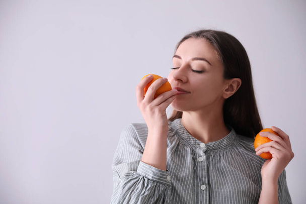 Woman with fresh tangerines on light grey background. Space for text - Foto, Imagem