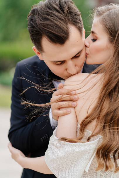 beautiful, gentle and happy bride and groom. man gently kisses womans shoulder - Fotó, kép