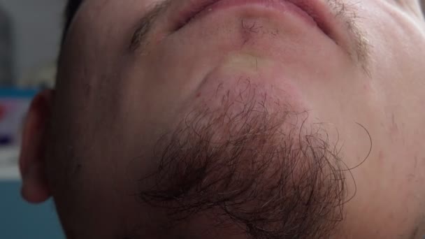 Close-up van een jonge man met een baard die zijn baard aanraakt. selectieve focus - Video