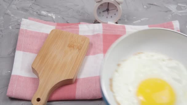 Alarm saati ve gri bir arka planda çırpılmış yumurta. Kopyalanacak yer de var. Günaydın. - Video, Çekim