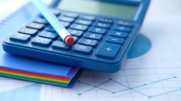 Primer plano de la calculadora azul y gráfico financiero en la tabla. - Imágenes, Vídeo