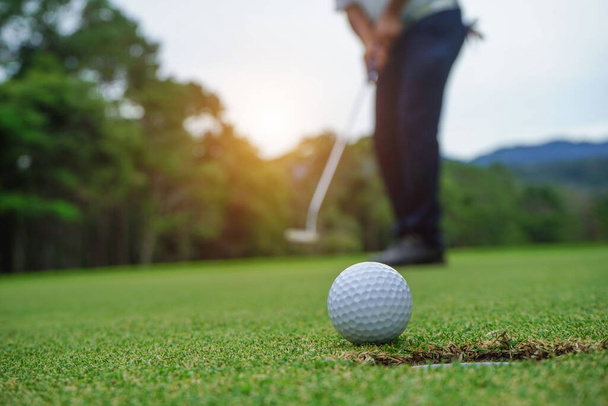 Golfista desfocado jogando golfe no campo de golfe à noite, ao pôr-do-sol hora da noite. Homem jogando golfe em um campo de golfe ao sol.                                - Foto, Imagem