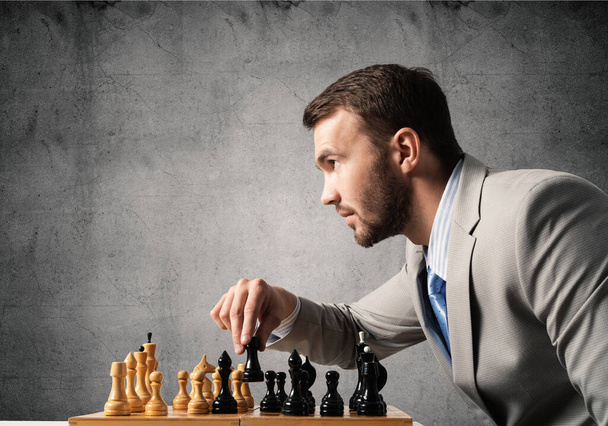 Concentrated businessman playing chess game - 写真・画像