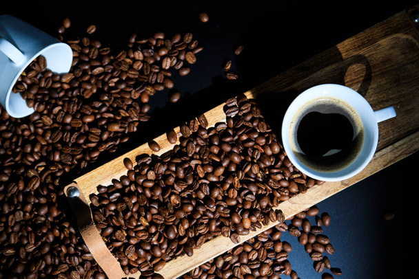 Detailní záběr na šálek kávy s praženými kávovými zrny na dřevěném pozadí. - Fotografie, Obrázek