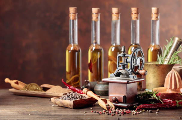 Старий перець з кухонним начинням, пляшками оливкової олії, спеціями та розмарином на дерев'яному столі
. - Фото, зображення
