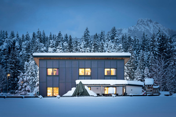 Vista frontale di una casa unifamiliare con facciata solare termica per un riscaldamento sostenibile e rinnovabile e acqua calda di notte in inverno - Foto, immagini