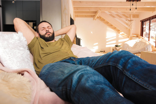 молодой человек с бородой лежит на животе в кровати и использует ноутбук, выборочный фокус. - Фото, изображение