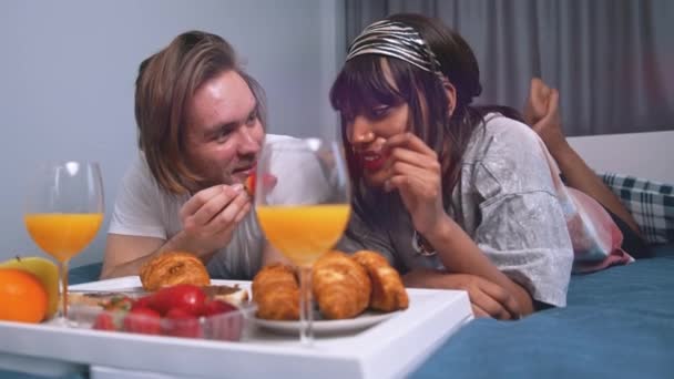 Snídaně do postele. mladý pár jíst snídani v posteli v hotelovém pokoji - Záběry, video