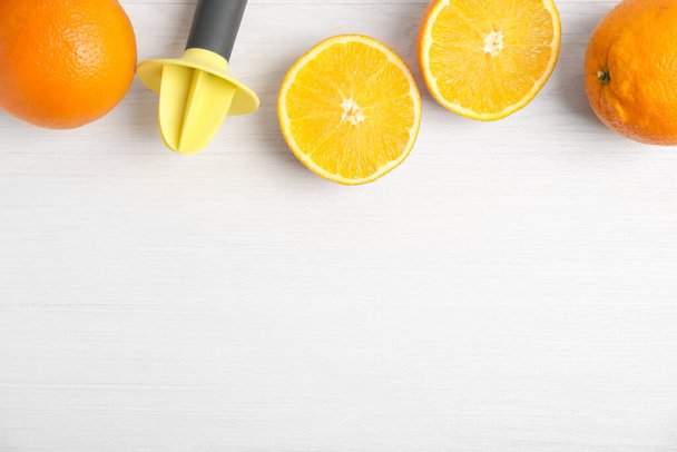 Fresh ripe oranges and reamer on white wooden table, flat lay. Space for text - Valokuva, kuva