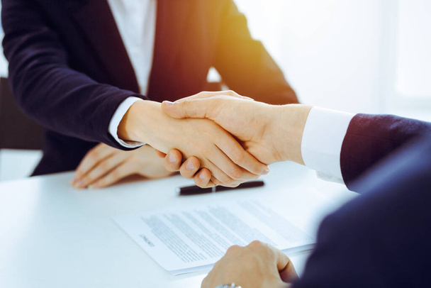 Businesspeople or lawyers shaking hands finishing up meeting or negotiation in sunny office. Business handshake and partnership - Фото, изображение