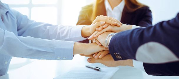 Business team showing unity with their hands together in sunny office. Group of people joining hands and representing concept of friendship and teamwork - Foto, Imagen