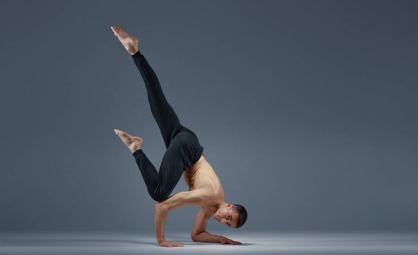 Male yoga keeps balanc in difficult pose on hands - Photo, Image