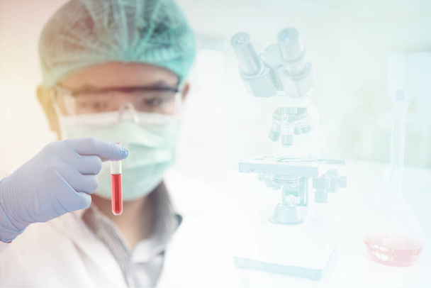 Gli scienziati indossano indumenti protettivi mentre tengono la provetta in laboratorio. - Foto, immagini