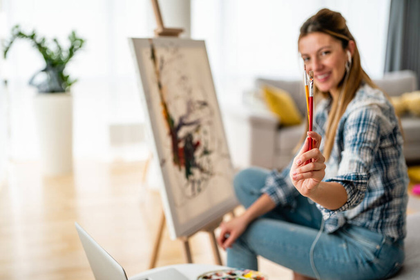 Art, creativity, hobby, job and creative occupation concept. Beautiful woman painting at home. - Fotoğraf, Görsel