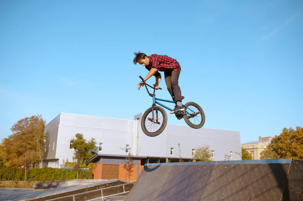 Male bmx biker jumps on ramp in skatepark - Photo, Image