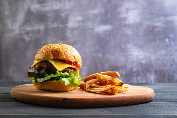 frische, leckere hausgemachte Hamburger mit frischem Gemüse, Salat, Tomaten, Käse auf einem Schneidebrett mit Pommes frites. Freiraum für Text - Foto, Bild