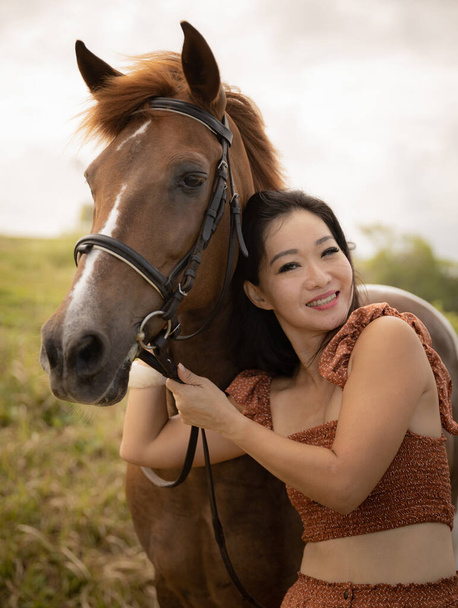 Ritratto di donna felice e cavallo bruno. Donna asiatica che abbraccia un cavallo. Concetto romantico. Emozioni positive. Rapporti umani e animali. Concetto natura. Bali, Indonesia - Foto, immagini