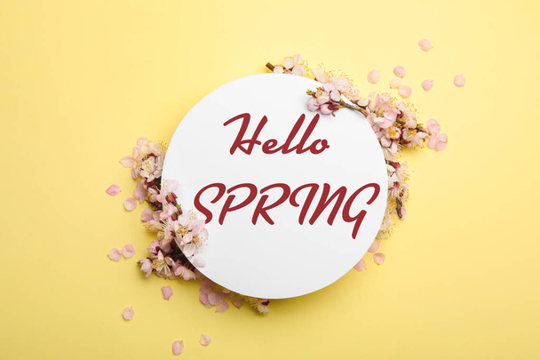 Beautiful flowers and card with text Hello Spring on yellow background, flat lay - Foto, Imagen