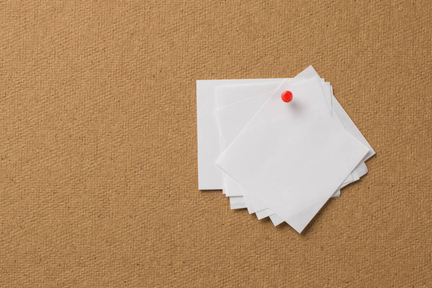 Foto de cerca de un montón de papel de apuntar blanco claro unido con un alfiler rojo al fondo de madera - Foto, Imagen