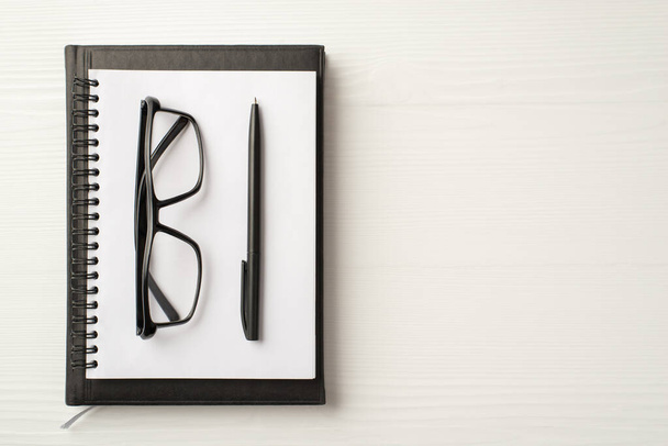 Top felett lapos nézet fotó komoly munkáltató bőr napló spirál másolópapír szemüveg és toll elszigetelt fehér háttér üres hely - Fotó, kép
