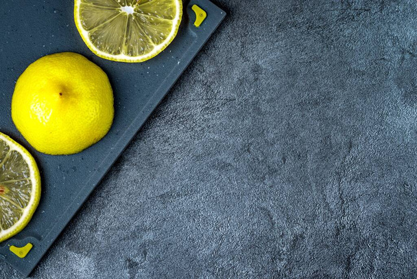 Limão fatiado em uma placa de plástico de corte contra o fundo de uma superfície de mesa de mármore. Close-up. - Foto, Imagem