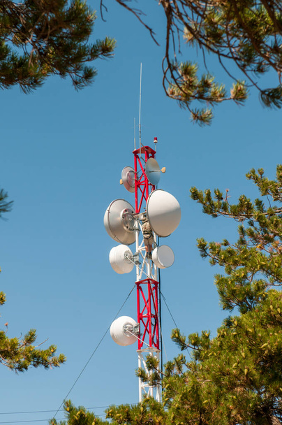 Kommunikationsturm auf einem Gebäude mit 4G-5G-Antenne vor blauem Himmel - Foto, Bild