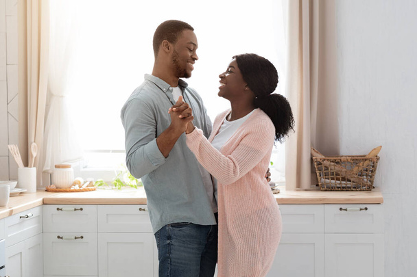 キッチン内で踊る幸せな黒人夫と妻 - 写真・画像