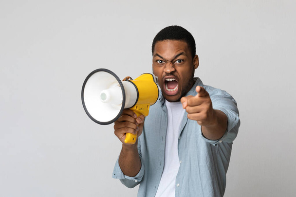 Fiatal fekete férfi kiabál hangosbeszélőben szürke háttér - Fotó, kép
