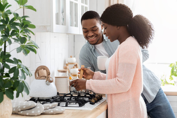 Koppels Huiselijk leven. gelukkig zwart echtgenoten koken lunch in keuken samen - Foto, afbeelding
