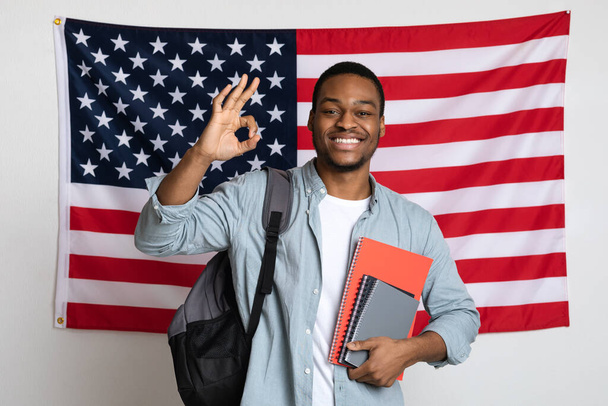 Souriant étudiant noir debout au-dessus du drapeau américain, montrant bien - Photo, image