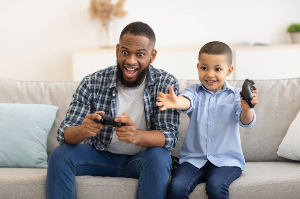 Afrikai apa és fia szórakozás videojáték a beltérben - Fotó, kép