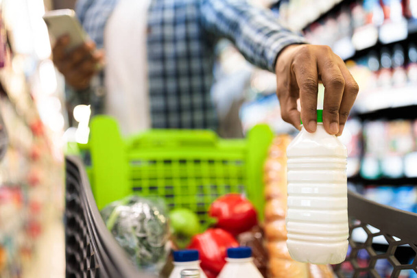Guy Doing Lebensmitteleinkauf Putting Produkte im Einkaufswagen im Supermarkt - Foto, Bild