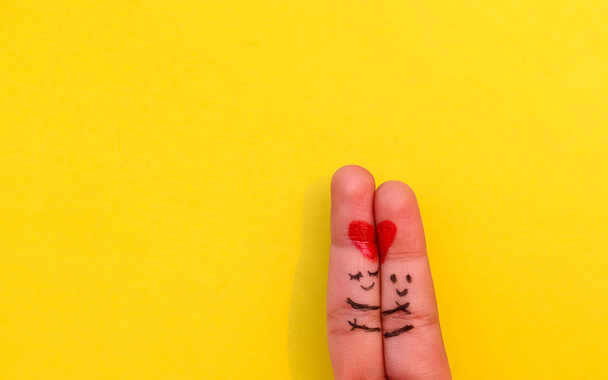 Fondo del Día de San Valentín, Una feliz pareja enamorada de sonriente pintado y abrazando el arte en el dedo. Concepto de San Valentín con fondo amarillo aislado con espacio. - Foto, Imagen