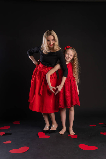 Girl and baby sign of love hands hold a happy Valentines background, heart flirting, on the floor hearts romance romance. Form. love formula of love, engagement in red girl dress, barefoot - Fotografie, Obrázek