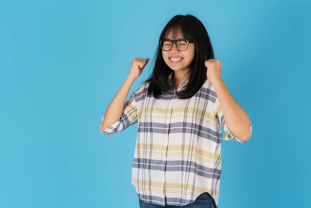 Felice sorridente ragazza asiatica in piedi su uno sfondo blu - Foto, immagini