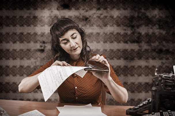 Νεαρή γυναίκα με κόκκινο φόρεμα συρραφή χαρτιά στο γραφείο, 1960 του - Φωτογραφία, εικόνα