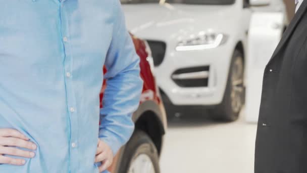 Mann erhält Autoschlüssel und schüttelt Autohändler die Hand - Filmmaterial, Video